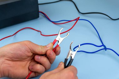 Adamın biri mavi arka planda bir takviye kablosu tutuyor. yakın plan