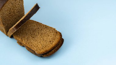 Yarım somun çavdar ekmeği ve dilimlenmiş, mavi arka planda yakın plan.