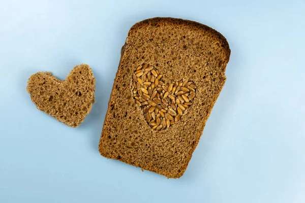 Kawałek Chleba Żytniego Środku Którego Wycina Się Serce Posypuje Pszenicą — Zdjęcie stockowe