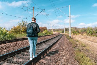 Beyaz ayakkabılarla demiryolunda yürüyen bir kız.
