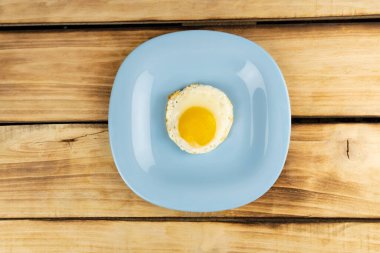 Mavi bir tabakta sahanda yumurta. Ahşap arka plan. Sağlıklı kahvaltı.