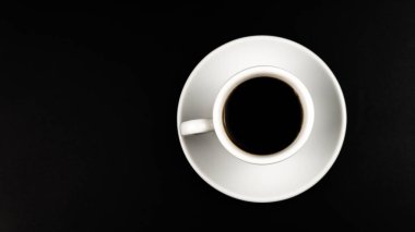 Siyah arka planda kahve ve çay tabakları olan beyaz fincanın üst görüntüsü