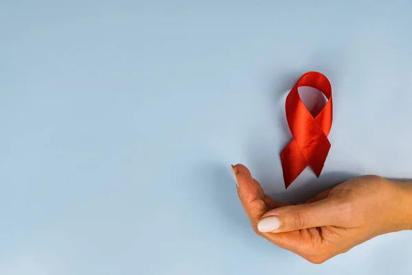 Vrouwenhand Vlucht Rood Lint Aids Dag Blauwe Achtergrond — Stockfoto