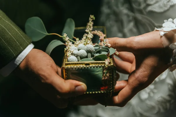 Нареченої і нареченого холдингу руки і красиві Весільні кільця на руці. Романтична пара, тримаючи один одному є руку за вечерею в саду. — стокове фото
