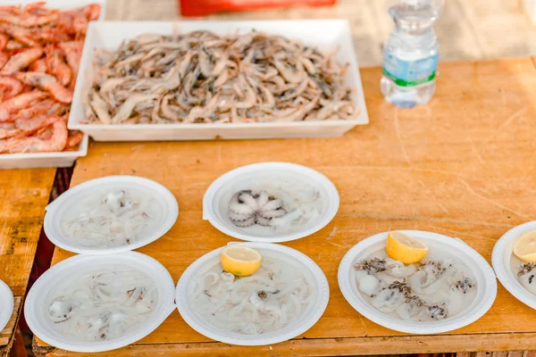 Ikan yang baru ditangkap, landak laut, tiram, sotong, gurita dengan lemon di pasar di dermaga St Nicholas di pusat kota Bari, daerah Puglia, Italia . — Stok Foto