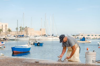 Bari, Puglia, İtalya - 07 Kasım, 2018: balıkçı üzerinde taze ahtapot yener St. Nicholas iskele bölgesinin Bari, Puglia, İtalya şehir merkezinde. liman ve deniz araçları.