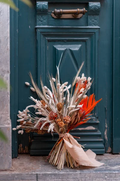Seikat bunga segar dengan daun hijau di pintu kayu di luar. Indah karangan bunga tendy dihiasi untuk pernikahan . — Stok Foto