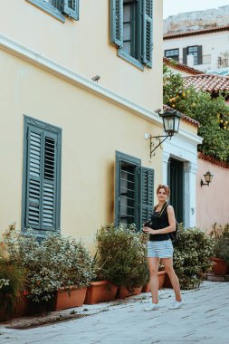 Güzel bir kız elinde bir kamerayla eski bir Avrupa kasabasının caddesinde yürüyor. Sokakta yürüyen bir turist kızın portresi..
