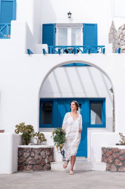 Beyaz elbiseli romantik gelin terasta poz veriyor. Arka planda dağlar ve deniz var.