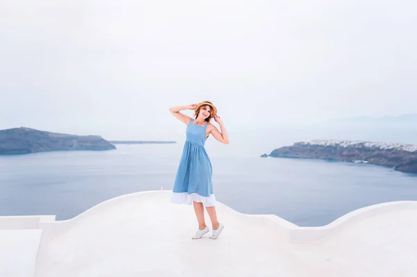 Mujer de vacaciones de lujo mirando en Santorini famoso destino de viaje de Europa. Elegante joven dama que vive estilo de vida jetset de lujo usando vestido en vacaciones. Increíble vista al mar y Caldera. — Foto de Stock