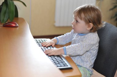 bilgisayar başında oturan klavye yazarak sevimli küçük bebek kız.