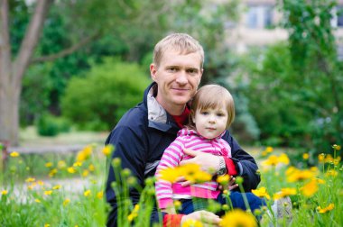 Mutlu genç baba ve küçük tatlı kızı doğadaki güzel parkta iyi eğlenceler..