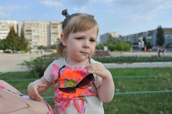 Aranyos kislány játszik a napos nyári parkban. A kisgyerek fut és ugrál az utcán. A gyerekek kint játszanak. Óvodás az iskola udvarán a meleg napon. — Stock Fotó