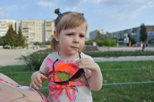 Aranyos kislány játszik a napos nyári parkban. A kisgyerek fut és ugrál az utcán. A gyerekek kint játszanak. Óvodás az iskola udvarán a meleg napon. — Stock Fotó