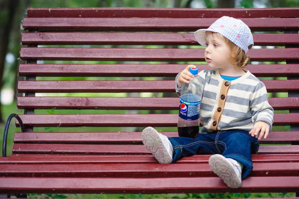 Small girl sitting on the bench in park — Stock Photo, Image