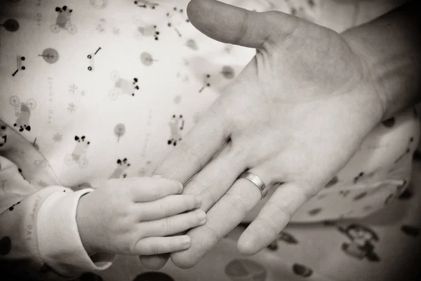 Geef de slapende baby in de hand van moeder close-up. Extreme close-up van een babys hand in moeders vinger. Close-up van babys hand houden moeders vinger — Stockfoto