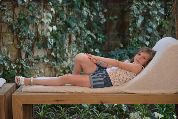 Giovane ragazza rilassante su una grande panchina parco tropicale all'aperto — Foto Stock