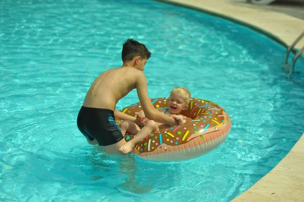 Children at pool, happiness and joy. Two brothers having fun swimming ring — Stock Photo, Image