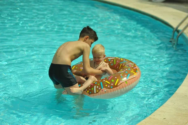 Дети у бассейна, счастье и радость. Два брата веселятся, плавая кольцо — стоковое фото