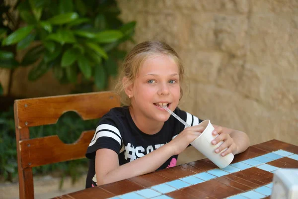 A menina bebe coquetel de leite em um café de rua. Férias de verão — Fotografia de Stock