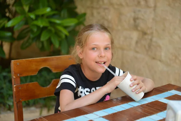 Une petite fille boit un cocktail au lait dans un café de rue. Vacances d'été — Photo