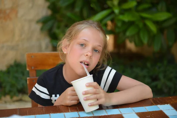 A menina bebe coquetel de leite em um café de rua. Férias de verão — Fotografia de Stock