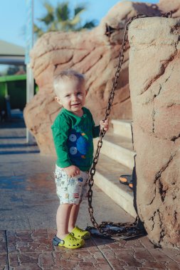 Deniz kenarındaki tropikal parkta yürüyen sevimli, mutlu küçük bir oğlan. Güzel bir yaz gününün tadını çıkarıyorum. Tatil kavramı