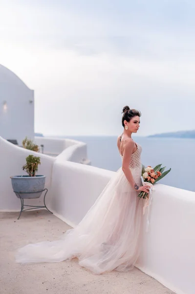 Romántico hermosa novia en vestido blanco posando en la terraza con el mar y las montañas en el fondo — Foto de Stock