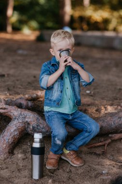 bir fincan çay açık havada tutan küçük bir çocuk. Çocuk çay içer