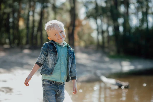 Retrato de menino sorridente bonito em uma margem do rio de verão . — Fotografia de Stock