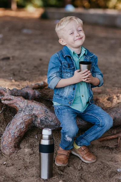 Kleine jongen een kopje thee buiten te houden. kind drinkt thee — Stockfoto