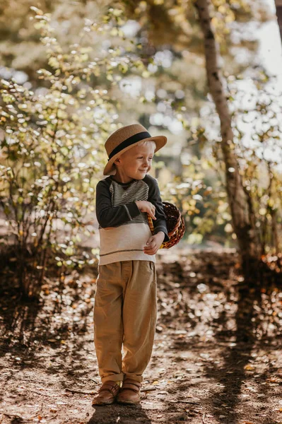 Rapaz elegante com um chapéu e um cesto. menino no parque em um chapéu com uma cesta no outono — Fotografia de Stock