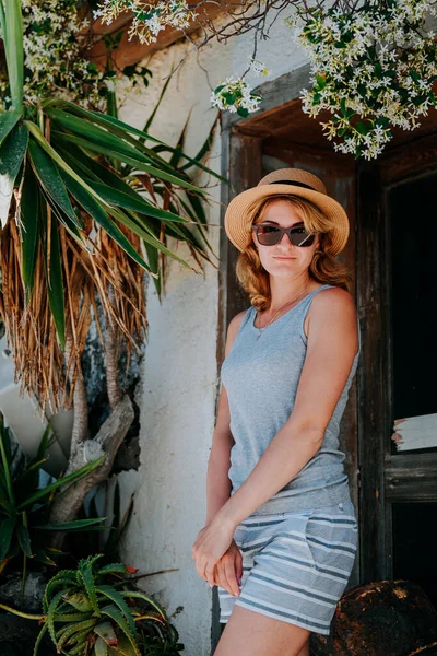 Luxusní krásná dívka v brýlích, v drahém hotelu na tropickém ostrově, na pozadí azurové mořské zátoky, na terase. Krásná blondýna dívka na ostrově Santorini Řecko — Stock fotografie