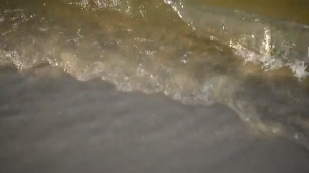 Detailní záběr mořských vln vyplavuje na břeh písečnou pláž. Mořská pěna na písku, zblízka. Detailní záběr zklidňující pěnové vody — Stock video