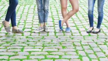 Bacakları kaldırımda duran farklı tarzlarda dört çift kadınlar