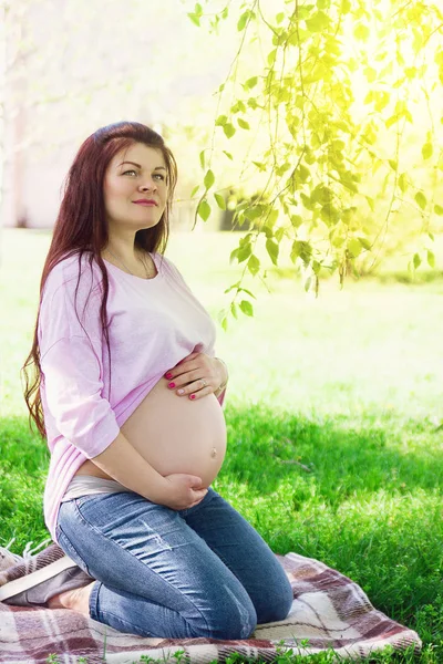 Happy Pregnant Girl Sitting Grass Hugging Belly Stock Image