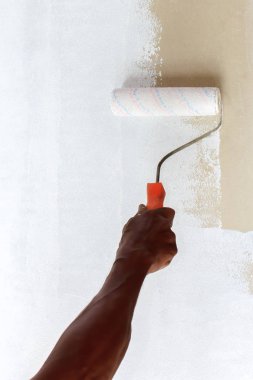 Birisi bir rulo kullanarak beyaz renk boya ile düz bir yüzey katman.
