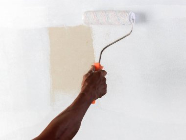 Birisi bir rulo kullanarak beyaz renk boya ile düz bir yüzey katman.