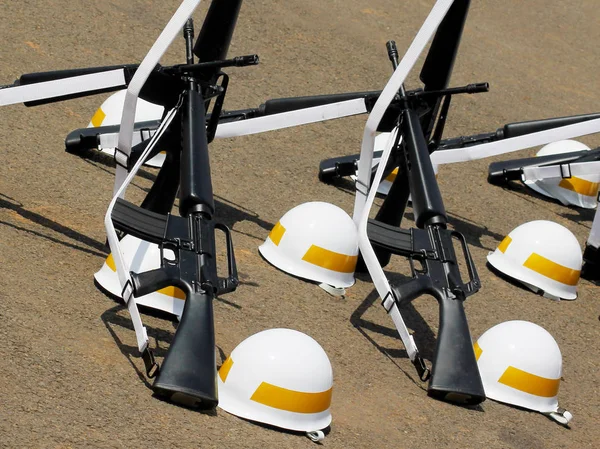 Saldırı tüfekleri ve sarı çizgili kask yere koydu.