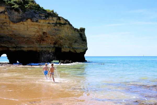 在葡萄牙南部 Estudantes 的美景 快乐的儿童玩耍 飞溅和游泳在海洋中最美丽的海滩在拉各斯 阿尔加维地区 免版税图库照片