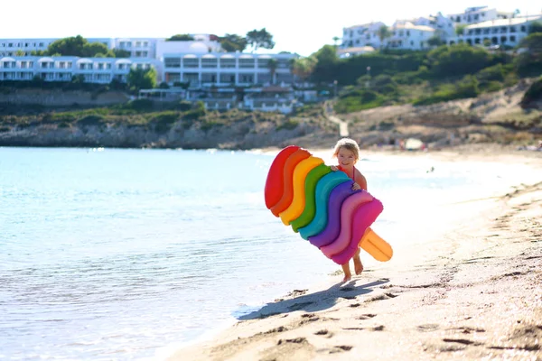 快乐的小女孩玩五颜六色的充气床垫在海洋或海洋 孩子在美丽的沙滩上玩得开心 可爱的孩子享受暑假在酒店或度假胜地 家庭与儿童的豪华夏季目的地 图库图片