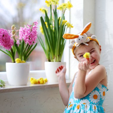 Bahar çiçekleri ve Paskalya yumurtaları ile pencere dekorasyon küçük kız. Bitkilerin bakımı çocuk. Sümbül ve nergis hakkında Bakımı yürümeye başlayan çocuk. Paskalya ev iç ve dekorasyon. 