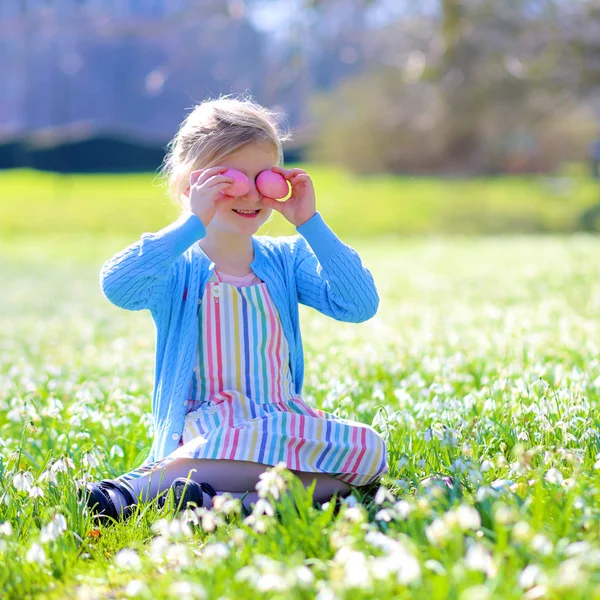 開花の伝統的なイースターエッグ ハントを楽しんでいるかわいい女の子春の庭 雪ドロップの花の草原でカラフルな卵をお探しの子 暖かい晴れた日の屋外で楽しんで子供 — ストック写真