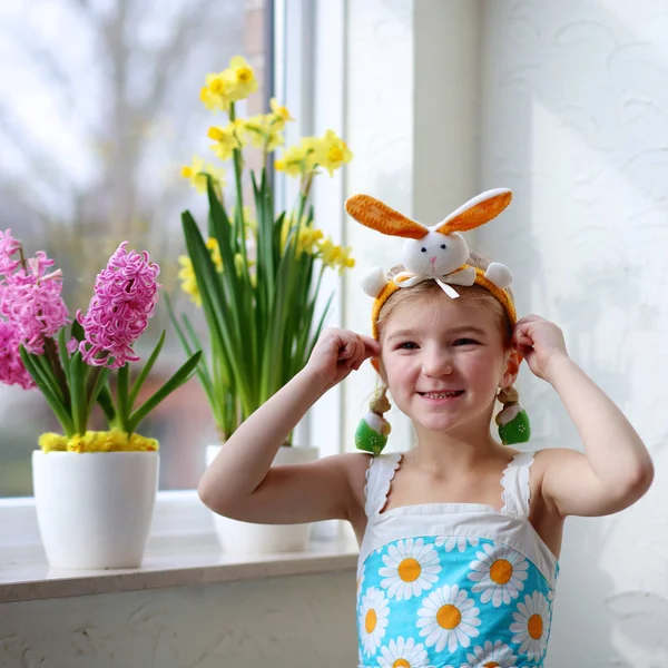 小女孩装饰的窗口与春天的花朵和复活节彩蛋 照看植物的孩子 幼儿照顾风信子和水仙花 复活节家庭内饰和装饰 图库照片