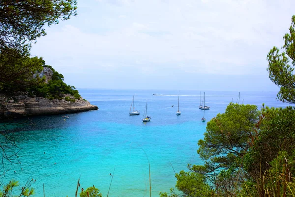 美丽的海湾在卡拉 Mitjana 梅诺卡岛 在西班牙的阿里岛 船在绿松石海水中航行 夏季家庭假期的理想目的地 图库图片