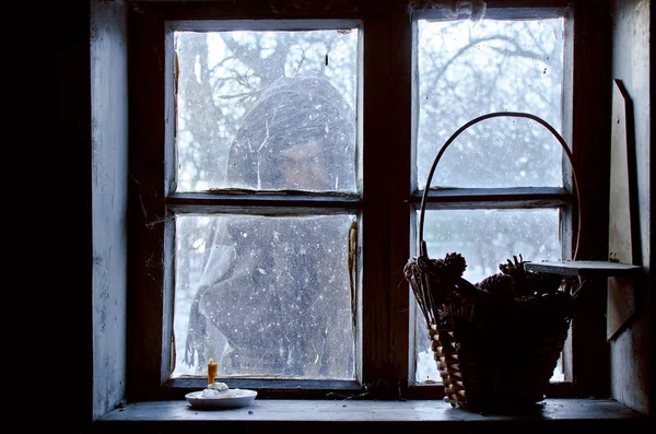 vague silhouette lost in the snow outside the window of a cozy house