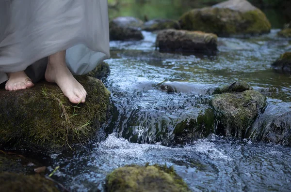 流れの速い川の中の石に裸足の女性の足 — ストック写真