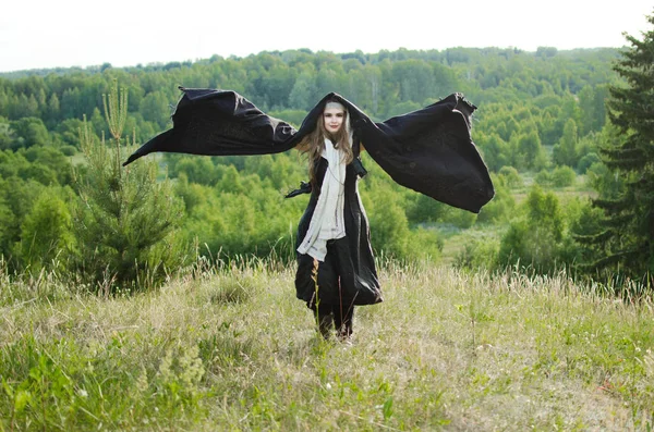 Young Witch Black Robe Stands Grassy Hill Raising Her Hands — Stock Photo, Image