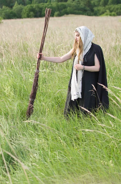 若い魔女でありフィールドに立っている 古い魔法のほうき — ストック写真