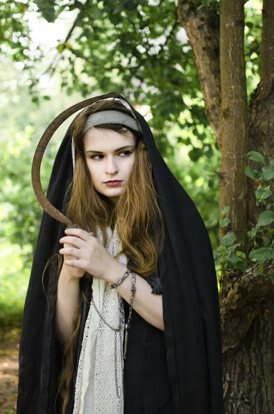 年轻的巫婆与锋利生锈的镰刀做了一件坏事环顾四周 — 图库照片